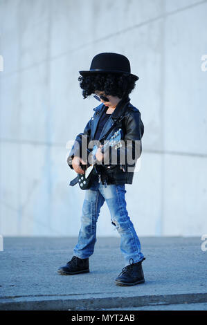 Un petit garçon mignon, guitariste de blouson de cuir et lunettes de jouer de la guitare. L'idole des jeunes. L'intérêt de l'enfant et passe-temps. Être comme une rock star. Banque D'Images