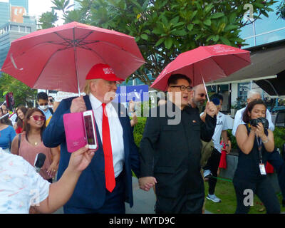 Singapour, Singapour. Le 08 juin, 2018. 08 juin 2018, Singapour : Howard X (L), souverain de la Corée du Nord de Kim Jong Un doppelganger, et Dennis Alan, le président américain Donald Trump's doppelganger, marcher main dans la main et de l'exécution un parapluie rouge à travers la ville. Credit : Zubaidah Jalil/dpa/Alamy Live News Banque D'Images