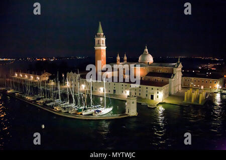 9 septembre 2014- Venise, Italie- île de Saint George's à Venise, avec clocher et la chapelle, éclairé la nuit avec des bateaux dans l'avant Banque D'Images