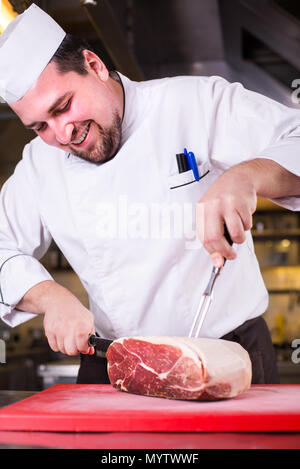 Smiling chef cutting grand morceau de viande Banque D'Images