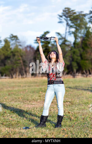 Young happy smiling woman holding up drone caméra vidéo à l'automne ou à l'automne avec des bottes dans le parc en campagne Virginia field hill ouvert jusqu'à Banque D'Images