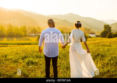 Couple en train de marcher sur le terrain avec vue sur le coucher de soleil romantique Banque D'Images