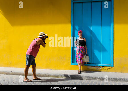 L'homme prend une photo d'une jeune fille à La Havane Cuba contre un mur jaune Banque D'Images