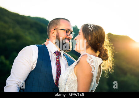 Bride and Groom hugging passionnément au coucher du soleil romantique Banque D'Images