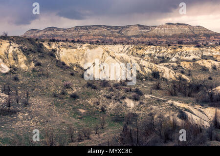 Paysage spectaculaire et rocheux avec des collines ondulantes et une végétation sèche sous un ciel nuageux, Vallée ; Cappadoce, Turquie Banque D'Images