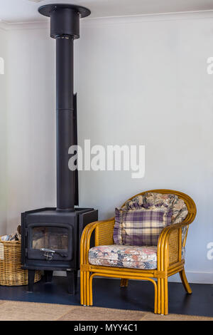 Chambre avec une chaise à côté d'un poêle à bois, avec une grande cheminée. Banque D'Images