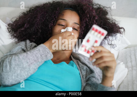 Femme au lit à la maison prendre des antibiotiques pour la grippe Banque D'Images