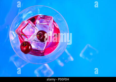 Verre à cocktail liqueur de cerise à partir de ci-dessus, sur un fond bleu. Boisson fraîche mise à plat avec copie espace