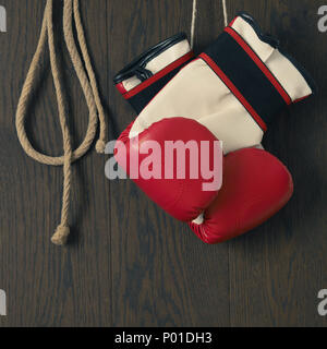 Gants de boxe rouge avec une corde à sauter sur un fond de bois Banque D'Images