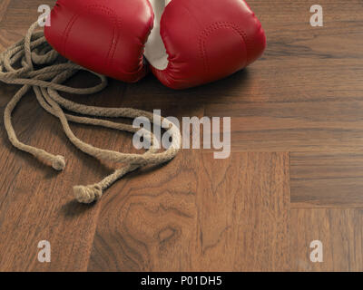 Gants de boxe rouge avec une corde à sauter sur un fond de bois Banque D'Images