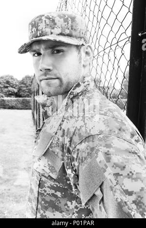 L'homme militaire armée musculaire en treillis et les stands à l'attention tout en gardant la base de l'armée Banque D'Images