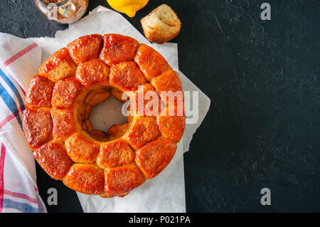 Caramel maison pain de singe avec le sucre brun et le zeste de citron sur un fond noir en noir Banque D'Images