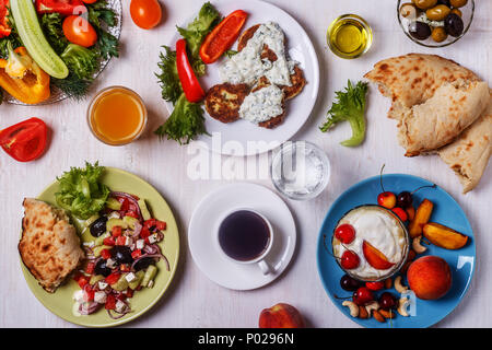 Apéritifs grecs - beignets de courgette avec sauce tzatziki, salade grecque, yaourt aux fruits et noix, olives, légumes et fines herbes, vue d'en haut. Banque D'Images