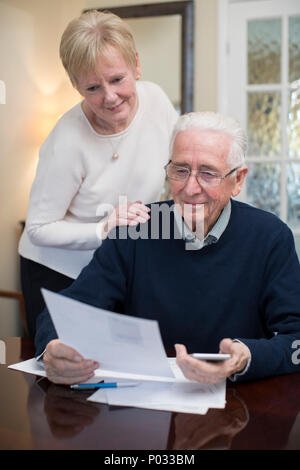 Happy Senior Couple d'examiner ensemble les finances nationales Banque D'Images