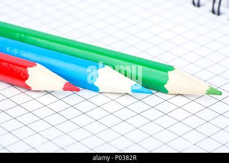 Trois crayons, rouge, vert et bleu sont l'ordinateur portable ouvert dans une cellule Banque D'Images
