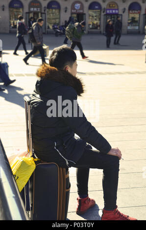 L'homme est assis sur une assurance lors de l'attente en face de la gare de Pékin Banque D'Images