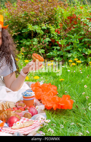 Une fille dans un chapeau orange sur un pique-nique. Célébration de la journée du Roi des Pays-Bas. Le ressort . Pré Vert et de fleurs. Espace libre pour le texte. Photo verticale, Banque D'Images