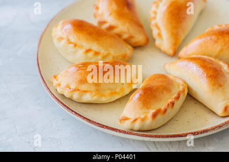 De pommes de terre maison empanadas farcies sur une plaque. Arrière-plan de pierre blanche. Close up. Banque D'Images