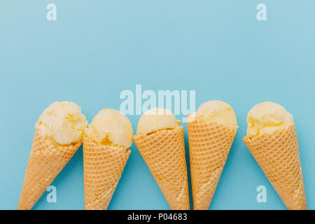 Cinq délicieuses glaces en cônes alvéolés sur fond bleu Banque D'Images