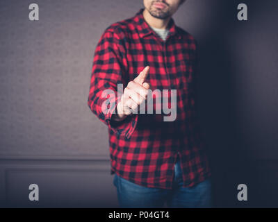 Un jeune homme portant une chemise de flanelle rouge pointe Banque D'Images