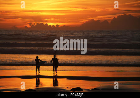 Photo d'un couple de surfeurs, sur la plage, au coucher du soleil Banque D'Images
