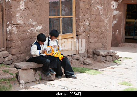 Deux garçons de l'école d'attendre d'être recueillies sur l'île de Taquile, le lac Titicaca. Pérou Banque D'Images