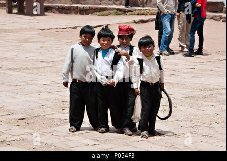 Les jeunes garçons se rassembler autour de poser pour une photo en échange de bonbons et de friandises dans le village à l'île de Taquile, le lac Titicaca. Pérou Banque D'Images