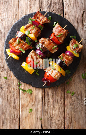 Délicieux chaud grill shish kebab de porc aux légumes, servi sur une plaque en ardoise close-up sur une table.Vertical haut Vue de dessus Banque D'Images