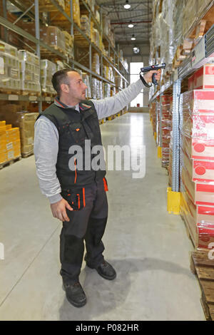 Travailleur dans l'entrepôt de distribution avec lecteur de codes à barres de poche Banque D'Images