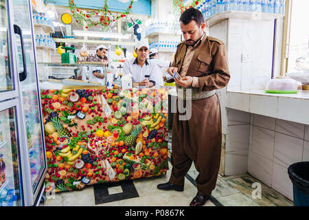 Le gouvernorat de Dohuk, Dohuk, Kurdistan irakien : un homme kurde en costume régional s'élève à un glacier dans la capitale provinciale de Doh Banque D'Images