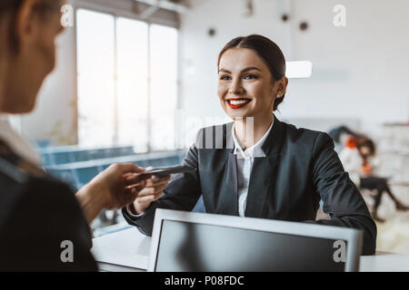 Attractive young businesswoman giving passeport et billet pour le personnel du comptoir d'enregistrement de l'aéroport Banque D'Images