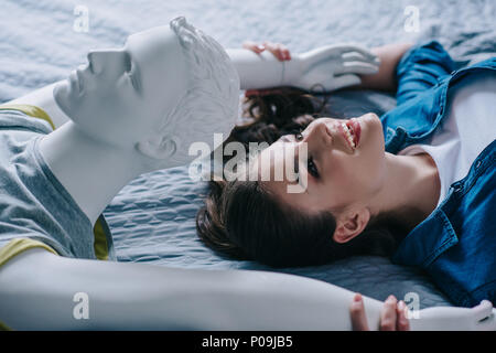 Vue latérale du mannequin et smiling woman lying on bed, solitude concept Banque D'Images