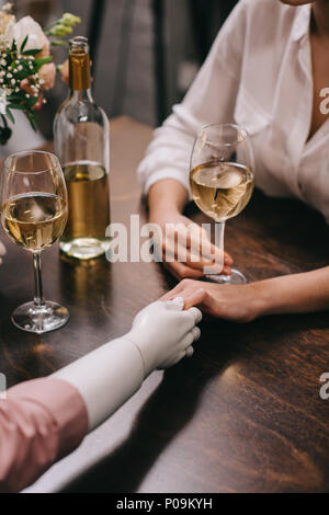 Cropped shot of woman holding hands mannequin et à table avec verres de vin, l'amour non partagé concept Banque D'Images