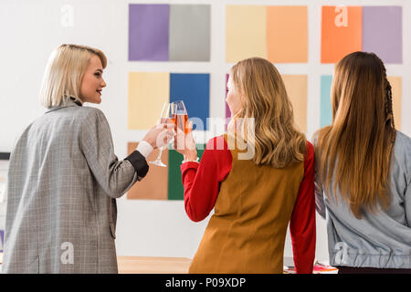 Les éditeurs de magazines de célébrer et de trinquer avec les verres de champagne in modern office Banque D'Images