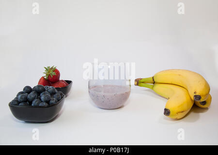 Smoothie aux fruits dans un vase en verre clair à base de banane, de bleuets et de fraises. Banque D'Images