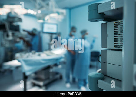 Médecin aidant à porter un uniforme chirurgicale sur arrière-plan flou Banque D'Images