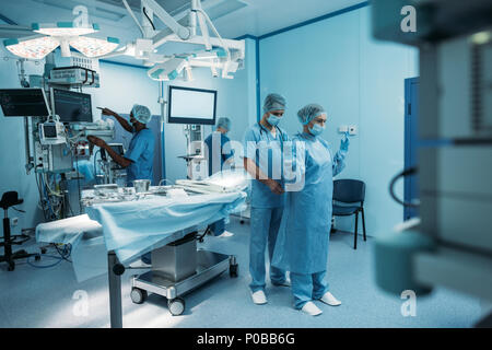 Médecin aidant à porter un uniforme en salle d'opération chirurgicale Banque D'Images