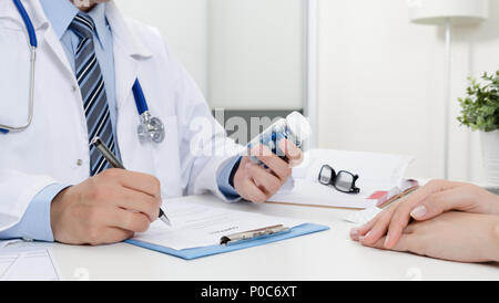 Le médecin et le patient à l'office. Docteur prescrit la recette. Tenant une bouteille de pilules. Banque D'Images