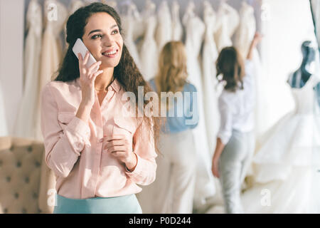 Femme parlant au téléphone tout en choisissant le salon du mariage en robe Banque D'Images