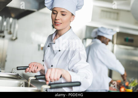 Chef attrayant grande friture dans l'huile à une cuisine de restaurant Banque D'Images