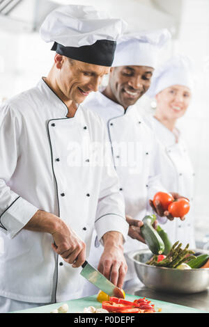 Smiling chefs cooking multiculturelle à une cuisine de restaurant Banque D'Images