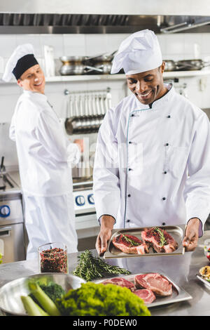 Heureux multicultural chefs cooking cuisine steaks au restaurant Banque D'Images