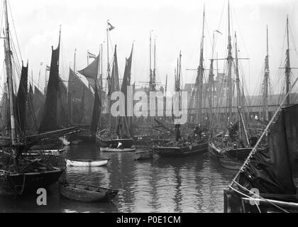 . Anglais : une vue de chalutiers dans le bassin à Lowestoft. Une vue de nombreux chalutiers à voile dans l'avant-port (éventuellement dans le bassin au chalut). Il s'agit notamment de 'Ivy' (1898) [LT160], "Qui vive" (1896) [LT702], 'Diamond croix" (1904) [R111], "Waverley" (1906), 'Mizpah' (1880) [LT214], et 'Children's Friend" (1900) [LT174]. Dans l'arrière-plan, on peut voir le pignon du nouveau bâtiment d'hébergement pour les pêcheurs. Vue des chalutiers dans le bassin à Lowestoft. . Vers 1908. Suitall Smiths Ltd 244 Vue des chalutiers dans le bassin à Lowestoft. RMG P27516 Banque D'Images