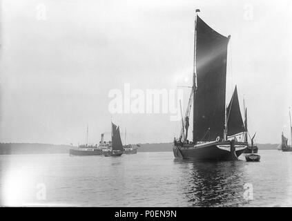 . Anglais : une vue de l'autre côté de la rivière Orwell à partir de l'axe avec l'usine près de barge spritsail Freston 'Tour' (1889) au premier plan. Une vue générale à la recherche de l'autre côté de la rivière Orwell à partir de l'axe près de Mill. Au premier plan est la spritsail 'barge Tour Freston' (1889) en vertu de la main et de l'artimon voiles, juste masquer une unidientified barge qui est à l'ancre. Le Great Eastern Railway 'Sussex ferry' (1895) est l'adoption d'une gaff rigged-location en retrait une offre dans la distance. Vue de l'autre côté de la rivière Orwell à partir de l'axe de près de moulin avec le chaland spritsail Freston 'Tower' (1889) au premier plan. . Vers 1904. Smiths Su Banque D'Images