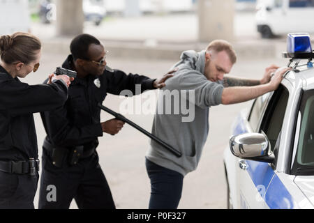 African American policier l'arrestation de jeune homme et d'une policière visant par pistolet Banque D'Images