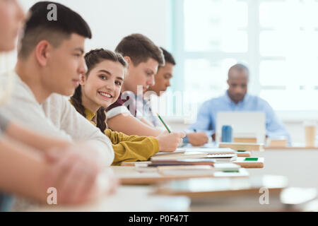 Groupe multiculturel de l'école secondaire élèves adolescents et enseignant à bureau avec ordinateur portable en salle de classe pendant la leçon Banque D'Images