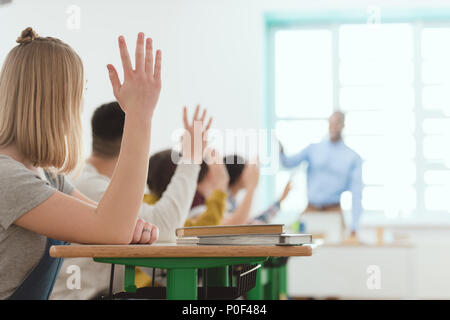 High school students raising hands pour répondre à la question des enseignants Banque D'Images