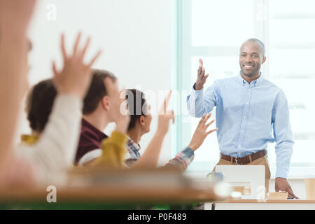 Smiling african american enseignant et élèves en classe avec les bras Banque D'Images