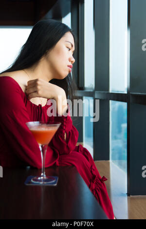 Pensive girl having a drink seul dans un bar Banque D'Images