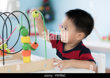 Tout-petits Asie adorable baby boy sitting on chair et en jouant avec des jouets de couleur à la maison. Banque D'Images